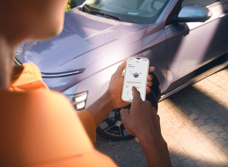 Hyundai Bluelink: a myHyundai app a telefonon egy Hyundai KONA Electric mellett